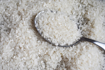 White rice background on table with iron spoon with rice. Top view