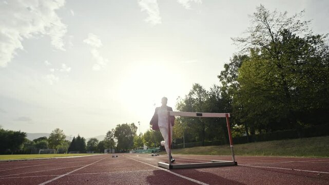 Businessman jumping a hurdle while running on the athletics racing track