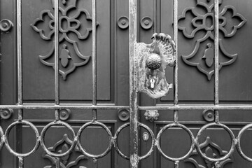 Close-up view of a heavily worn, ornate metal door handle and gate