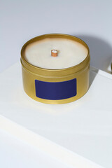 Luxury candle in a colorful tin with a blank label. Photograph with a white background and space for copy. Gold and blue design.