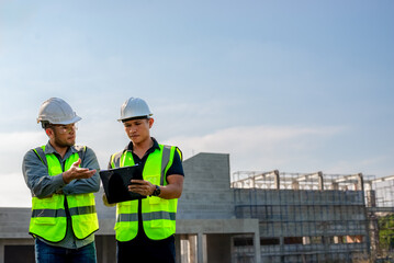 Two construction engineers are planning the construction of a building according to the building plan.