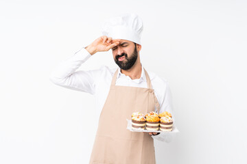 Young man holding muffin cake over isolated white background with tired and sick expression