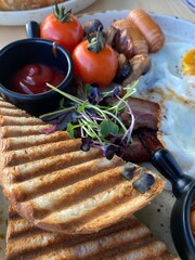 delicious breakfast with eggs, sausages, salad, croissants, tomatoes and cheese