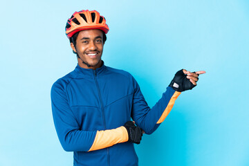 Young cyclist man with braids over isolated background pointing finger to the side