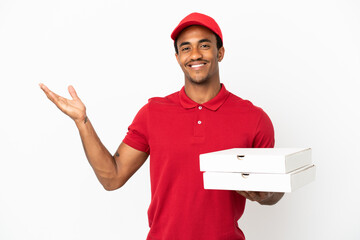 African American pizza delivery man picking up pizza boxes over isolated white wall extending hands...