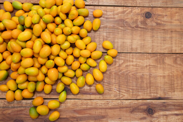 A pile of kumquat fruit on a wooden floor.