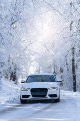 Car on a winter road through a snow covered forest.