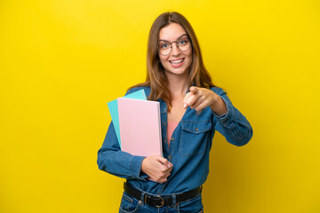 Fototapeta premium Young student caucasian woman isolated on yellow background surprised and pointing front