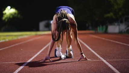 Female Runner on Athletics sprint race starting blocks on a dark background - Powered by Adobe