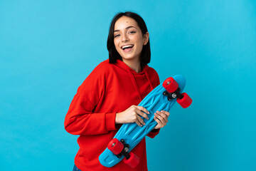 Young caucasian woman isolated on blue background with a skate with happy expression © luismolinero