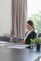 Middle aged asian woman working on documents data at contemporary office