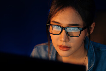 Portrait young beautiful Asian creative with glasses of serious face looking on pc to search project creator social media online, planning strategy creator at neon modern office at night. Stratagem.