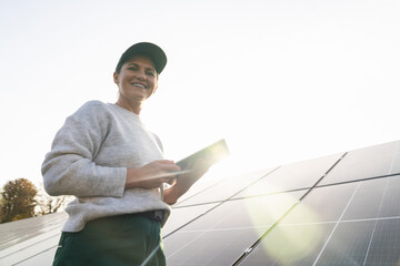 Female farmer with digital tablet on a modern farm using solar panels.