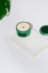 Luxury candle in a colorful tin with a blank label. Photograph with a white background and space for copy. Green design.