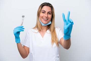 Dentist woman holding tools isolated on white background smiling and showing victory sign