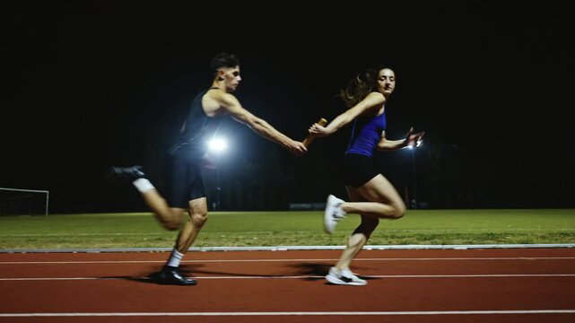 Athletes couple, male and female running a relay race and pass the baton on the athletics race track