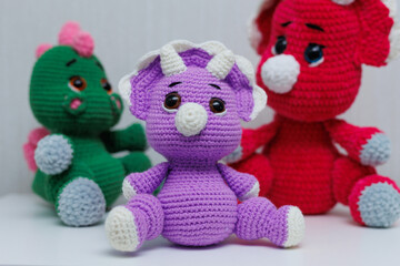 Knitted handmade dinosaur toys on a white background.