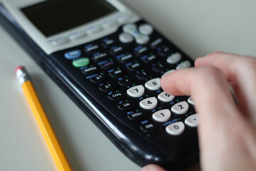 macro close-up of person using calculator with pencil on table isolated on white education or...