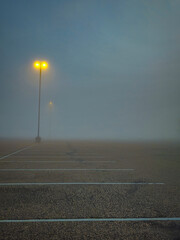 empty parking lot on foggy morning with tall light poles background © Caroline