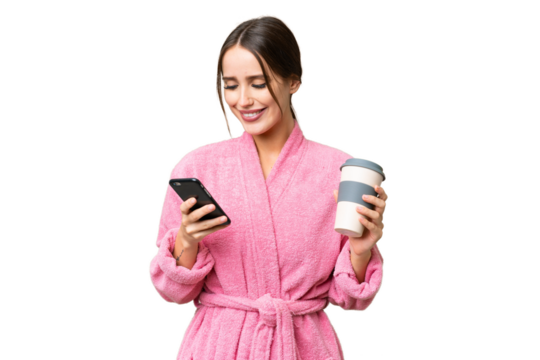 Young beautiful woman in a bathrobe over isolated chroma key background holding coffee to take away and a mobile
