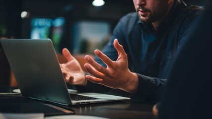 Strategic Partnership: Two professionals are engrossed in a focused discussion, their hands actively engaged in a dynamic exchange that suggests a shared project or collaborative effort.