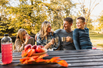 Family Sitting On Bench And Drinking Tee