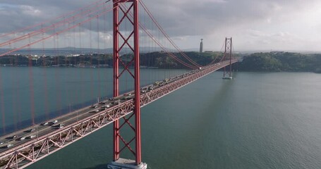 Cinematic aerial drone shot towards the 25th April Bridge, Ponte 25 de Abril, and Cristo Rei in Lisbon, Portugal, Europe. Afternoon with clouds. Shot in 5K ProRes 422 HQ Log