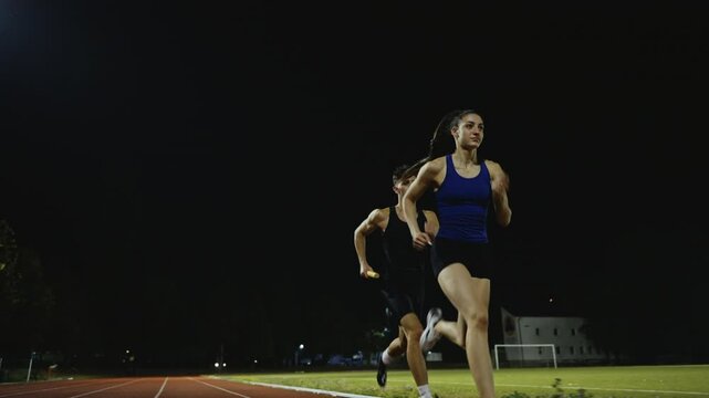 Athletes couple, male and female running a relay race and pass the baton on the athletics race track