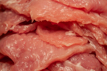 Raw pork cutlets are stacked together, showing their pale pink color and moist texture