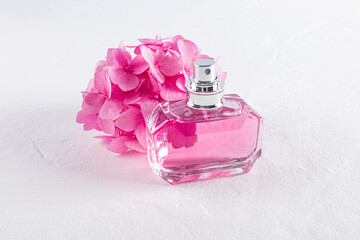 Elegant perfume bottle beside a cluster of pink flowers