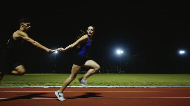 Athletes couple, male and female running a relay race and pass the baton on the athletics race track