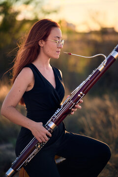 Woman playing bassoon in a tranquil field setting
