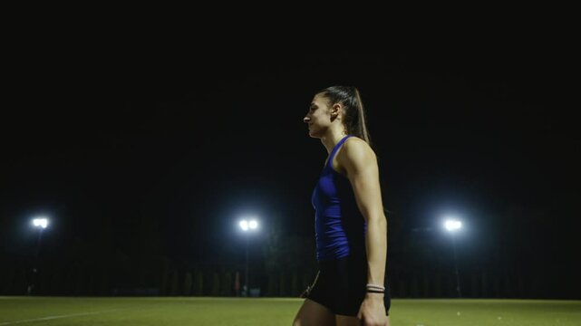 Female Athlete is playing with a relay race baton on the athletics race track after a successful competition race