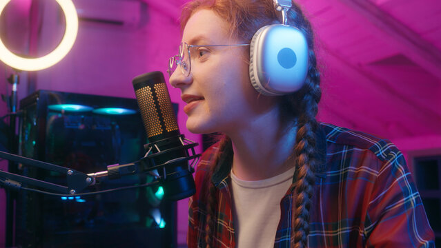 Happy girl female woman teen gamer in headphones radio host blogger influencer social media record podcast vlog online stream play computer video game cyber gaming addict chat talk microphone in neon