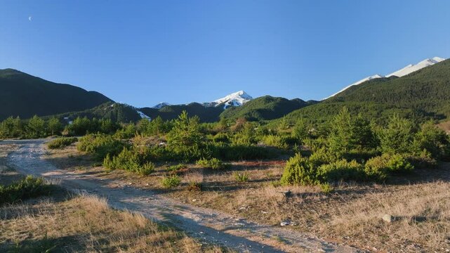 Flying to the left overviewing Piring Mountains near Bansko, prominent peak Todorka is covered in snow despite mid Spring season.