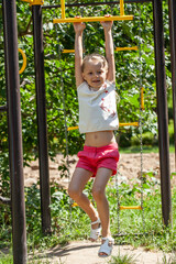 Little girl posing on playground in summer yard