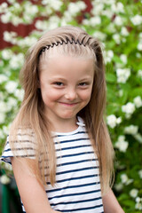 Close up portrait of a seven year little girl, against background of summer park