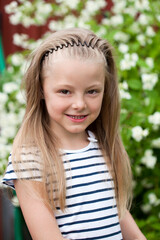 Close up portrait of a seven year little girl, against background of summer park