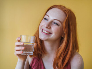 Mujer joven pelirroja, sostiene un vaso de agua