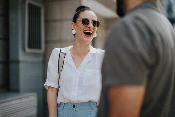 Business people discussing work in an outdoor meeting. Professional woman smiling and talking with a colleague on a sunny day.