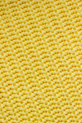 Diagonal texture of autumn light lemon yellow sweater. Knitted vertical banner. Selective focus, copy space