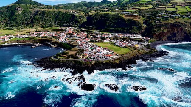 Mosteiros town. Aerial 4K drone video footage of village at Sao Miguel island, Azores. Located on the Atlantic ocean shore with big turquoise waves and mountains