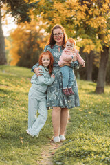 Fototapeta premium Young mom with her little ginger daughters. Mothers day, connection