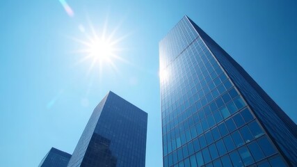Fototapeta premium skyscrapers with reflective glass windows against a clear blue sky, sun shining in the background, representing urban architecture.