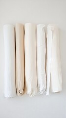 Fototapeta premium Cream and White Fabric Rolls Displayed on a White Background
