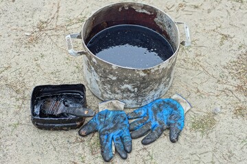 used black car engine dirty hazardous oil in aluminum pan stands on ground together with small...