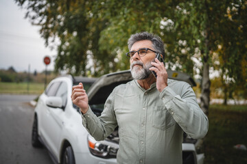 worried man stand in front open hood of car make a phone call for help