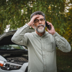 worried man stand in front open hood of car make a phone call for help