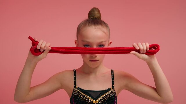 Little girl sportswoman female gymnast acrobat ballerina dancer with skipping rope in pink studio sport class education strong serious child looking camera kid daughter schoolgirl teen workout ballet