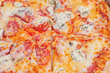 Pizza with cheese and sausages in a cardboard box, macro photo.